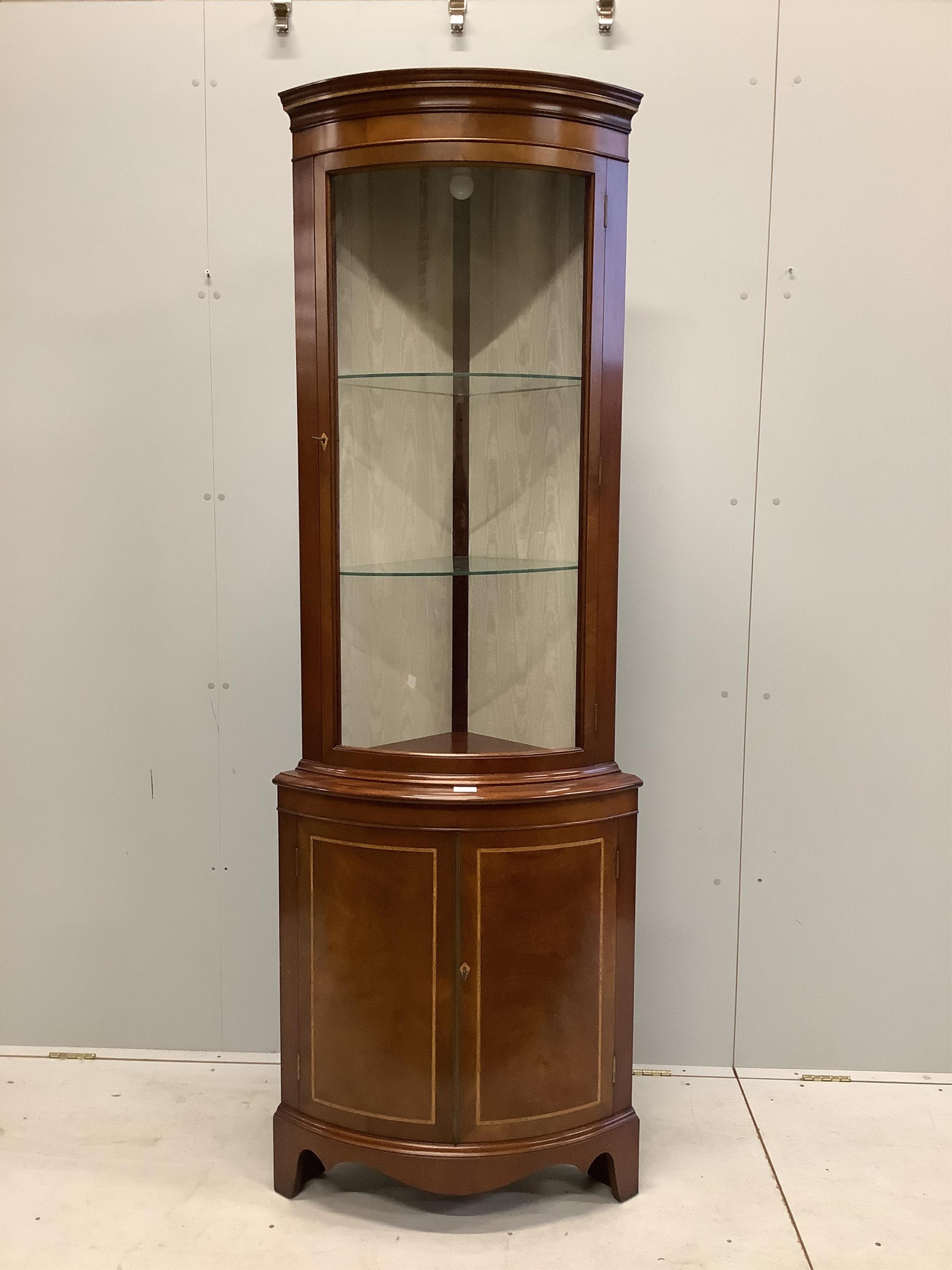 A reproduction Sheraton style inlaid mahogany bow fronted standing corner cupboard, width 70cm, depth 46cm, height 203cm. Condition - good